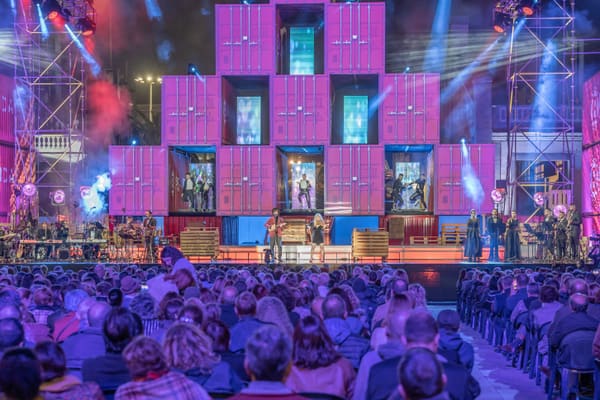 Concierto nocturno en el Parque de Santa Catalina, con el escenario de contenedores iluminado y el público sentado